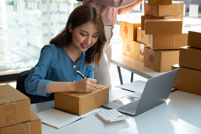 Female entrepreneur writing on box