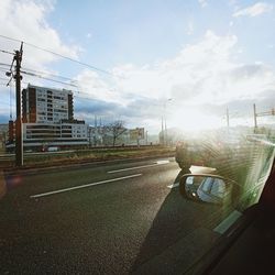 Road by buildings in city against sky