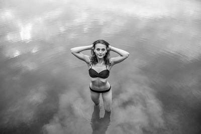 High angle portrait of young woman wearing bikini standing in lake