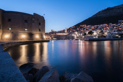 River by illuminated city against sky at night