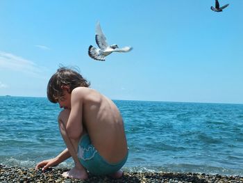 Low angle view of shirtless man in sea against sky