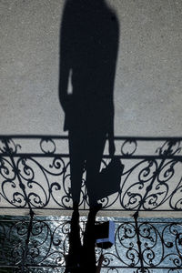 Shadow of person on railing against wall