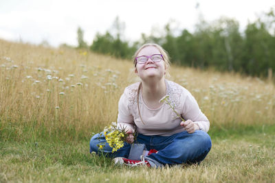 Smiling girl on meadow holding wildflowers