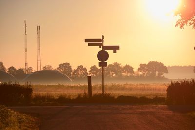 Street amidst field against sky during sunset