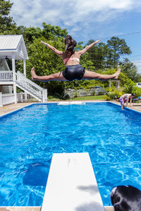 Reflection of woman jumping in swimming pool