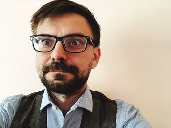 Portrait of man wearing eyeglasses against wall