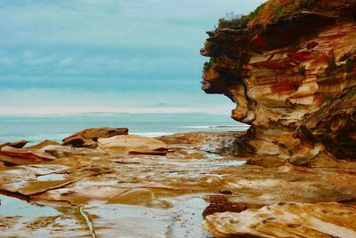 Rock formation on beach against sky