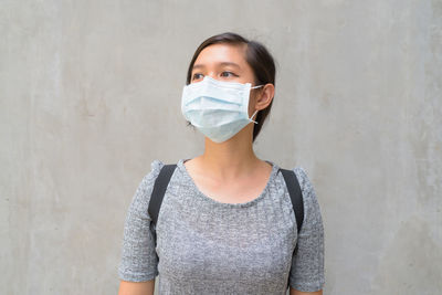 Portrait of young woman standing against wall