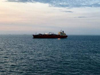 Ship in sea against sky during sunset