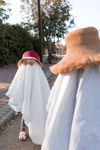 Trendy sheet ghosts costumes on little kids standing on a suburbs street. happy halloween holiday