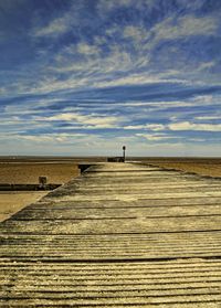 Pier at beach against sky