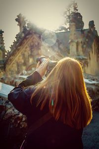 Rear view of woman at looking at historic building through binoculars