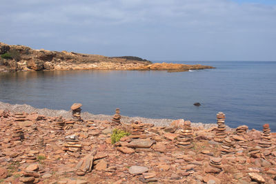 Stones stacked on sea shore against sky