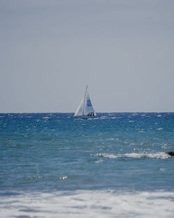 Sailboat sailing on sea against clear sky