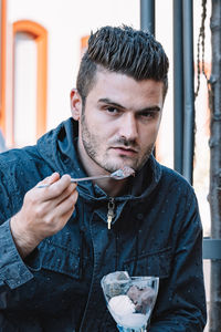 Portrait of young man holding sunglasses