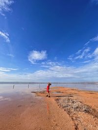 Rear view of woman walking at beach against sky
