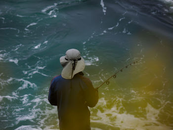 High angle rear view of man fishing in sea