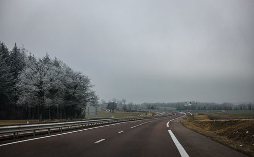 Road amidst trees against clear sky