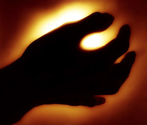 Close-up of human hand against illuminated light