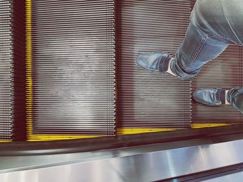 Low section of man standing on escalator