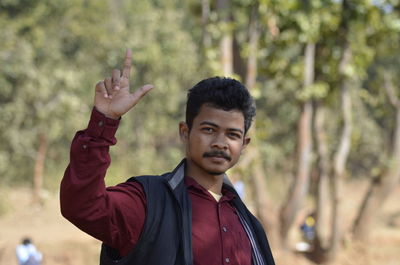 Portrait of young man standing against trees