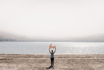 Man standing with love text at beach against sky