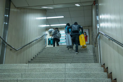 Rear view of people walking on staircase in subway