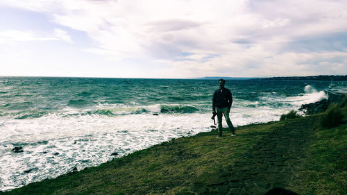 Rear view of people standing on beach against sky