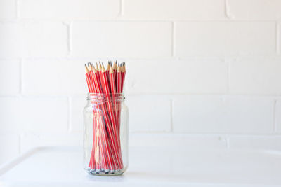 Close-up of glass jar on table against wall