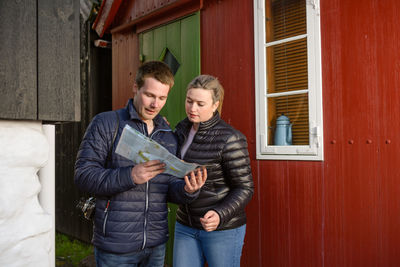 Young man and woman standing against wall