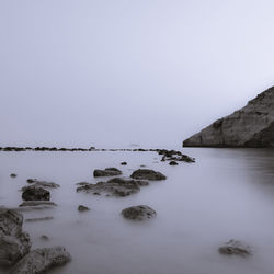 Rocks in sea against clear sky