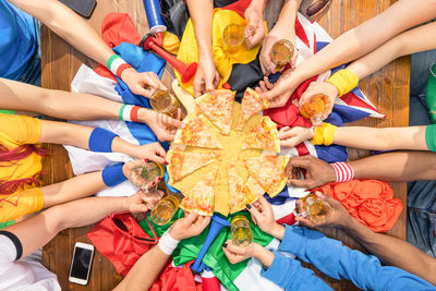 High angle view of cropped hands picking pizza slices from table