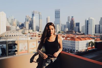 Portrait of young woman standing against building in terrace