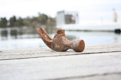 Close-up of rusty metal on pier against sky