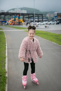 Smiling girl inline skating on road in city