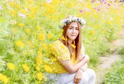 Portrait of smiling young woman against yellow flowering plants