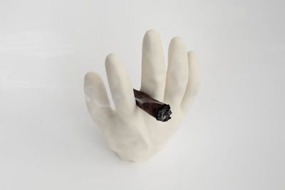 High angle view of glove with burning cigar over white background