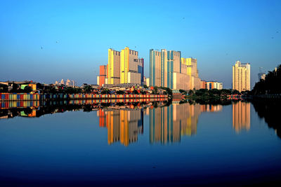 Reflection of buildings in river against blue sky