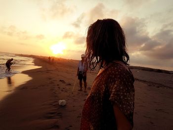 Woman on beach against sky during sunset