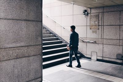 Rear view of man walking on staircase of building