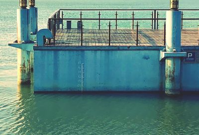 Blue railing by sea against sky