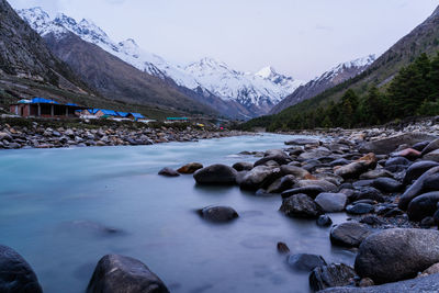 Scenic view of river by mountains against sky