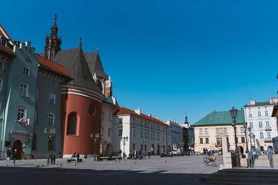 Street amidst buildings against clear blue sky