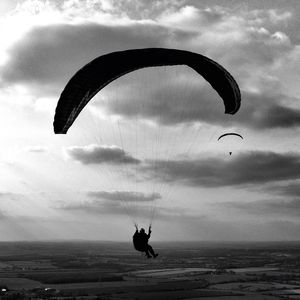 Low angle view of kite flying in cloudy sky