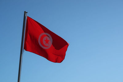 Low angle view of tunisian flag against clear blue sky