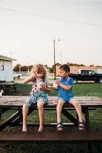 Two young kids eating snow cones outside at sunset