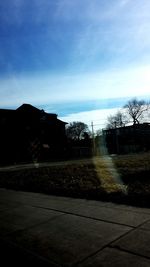 Trees on road against cloudy sky