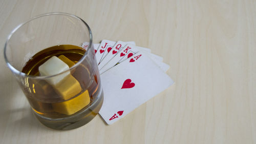 High angle view of whiskey glass with playing cards on table