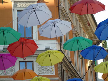 Multi colored umbrellas hanging against sky