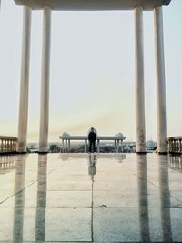 Rear view of man standing on pier against sky